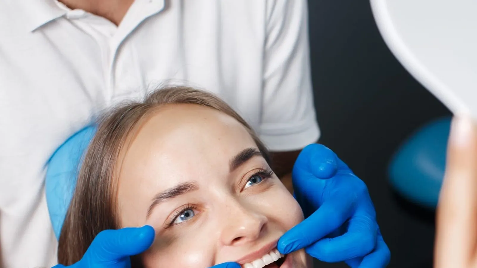 Patiente souriante lors d'une consultation dentaire dans une clinique accréditée d'Istanbul, dentiste comparant la teinte de facettes en céramique