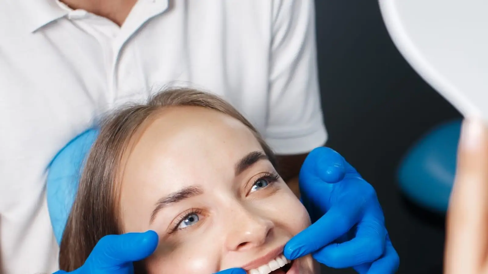Patiente souriante lors d'une consultation dentaire dans une clinique accréditée d'Istanbul, dentiste comparant la teinte de facettes en céramique