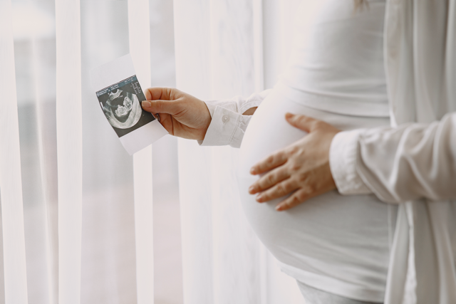 pregnant woman holding a photo of her baby 