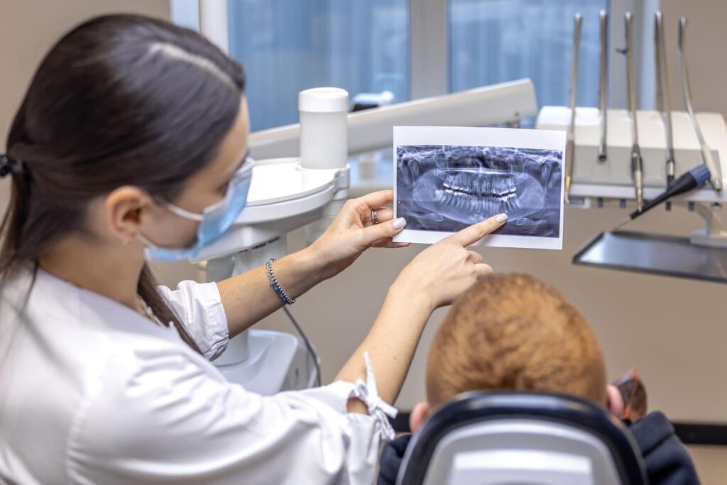 Dentist reviewing a panoramic dental X-ray with a patient to plan implants and cost